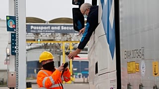 A lorry driver's documents are scanned on a phone as he passes a checkpoint for the train through the Eurotunnel link with Europe