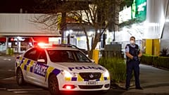 Police stand outside the site of a knife attack at a supermarket in Auckland.