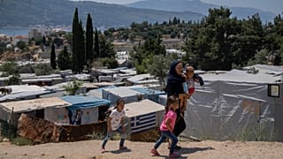 An Afghan woman with her three children walk outside the perimeter of the refugee camp at the port of Vathy on the eastern Aegean island of Samos, Greece, June 11, 2021.