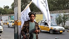 Un combatiente talibán sostiene su arma bajo las banderas talibanes colgadas en una calle de Kabul, Afganistán, el 30 de agosto de 2021.