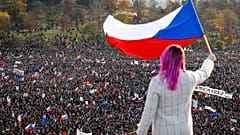 A woman waves a Czech flag from a roof as people take part in a large anti-government protest in Prague, Czech Republic, Saturday, Nov. 16, 2019