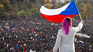 A woman waves a Czech flag from a roof as people take part in a large anti-government protest in Prague, Czech Republic, Saturday, Nov. 16, 2019