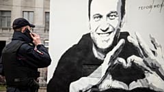 A police officer speaks on the phone near to graffiti of Russia's imprisoned opposition leader Alexei Navalny in St. Petersburg.