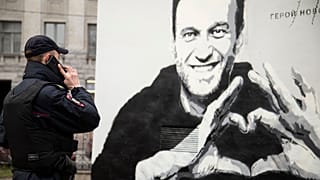 A police officer speaks on the phone near to graffiti of Russia's imprisoned opposition leader Alexei Navalny in St. Petersburg.