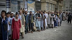 Afghans queue up as they wait for the banks to open and operate at a commercial area in Kabul on August 31, 2021.