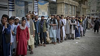 Afghans queue up as they wait for the banks to open and operate at a commercial area in Kabul on August 31, 2021.