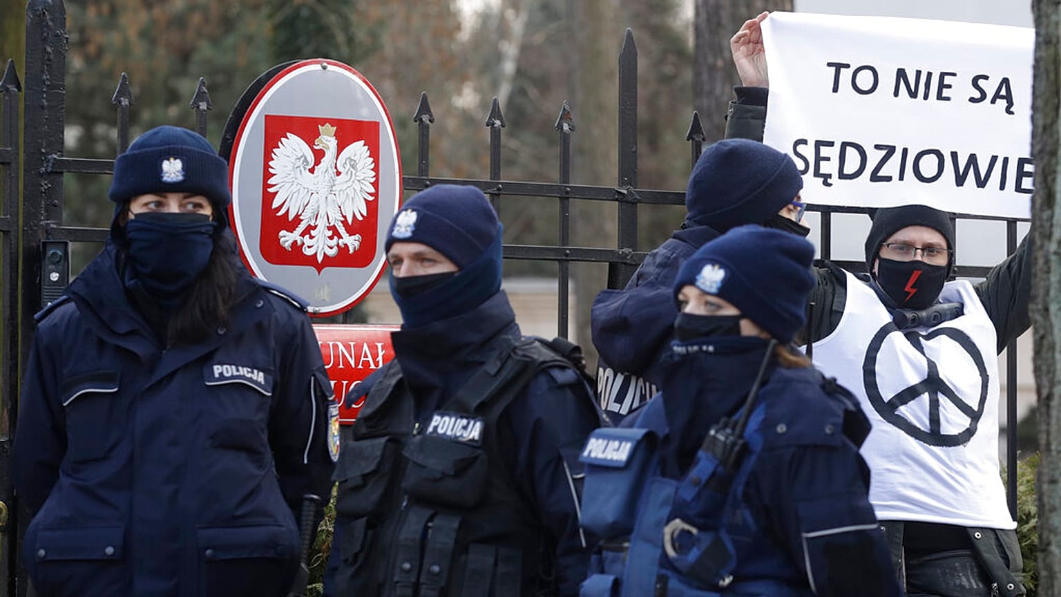 Police surround a protester who holds a sign saying in front of the Constitutional Court in Warsaw, Poland, Wednesday March 10, 2021