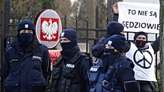 Police surround a protester who holds a sign saying in front of the Constitutional Court in Warsaw, Poland, Wednesday March 10, 2021