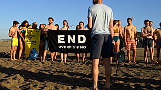 Participants gather and hold a banner on a beach in Marseille to draw the attention of world leaders and protest against the environmental crisis.