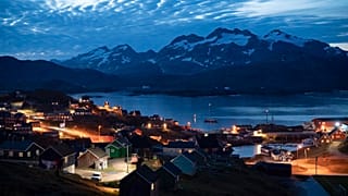 Homes are illuminated after the sunset in Tasiilaq, Greenland.