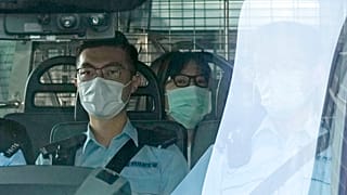 Chow Han Tung, vice chairwoman of the Hong Kong Alliance in Support of Patriotic Democratic Movements of China, center, is escorted by police in a van to a court, in Hong Kong