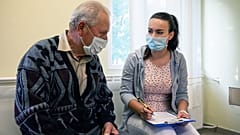 Somogyi Nóra asszisztens segít az oltási papírok kitöltésében egy férfinek, mielőtt beoltják AstraZeneca típusú oltással