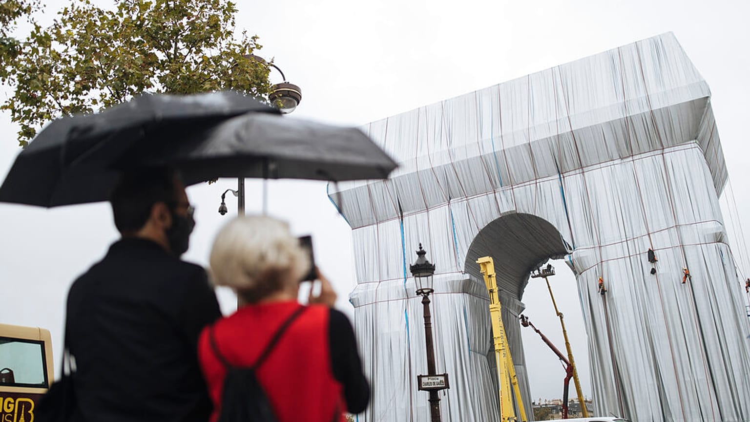 People watch workers wrapping the Arc de Triomphe ahead of the three-week installation on Wednesday