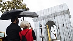 People watch workers wrapping the Arc de Triomphe ahead of the three-week installation on Wednesday