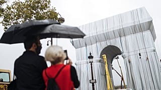 People watch workers wrapping the Arc de Triomphe ahead of the three-week installation on Wednesday