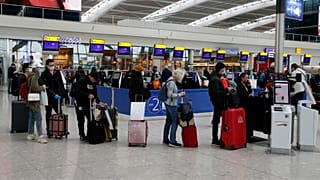 People queue at ticket machines at Heathrow airport in London, Wednesday, March 18, 2020. 