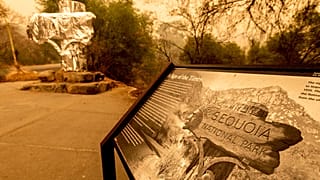 Fire-resistant wrap covers a historic welcome sign as the KNP Complex Fire burns in Sequoia National Park, Calif., on Sept. 15, 2021.