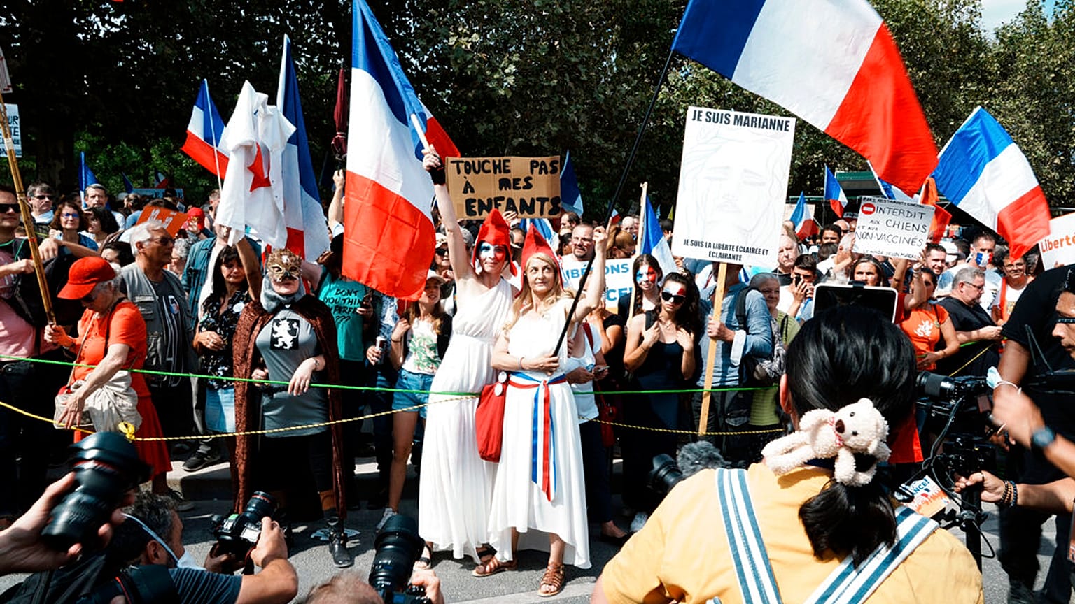Protesters dressed as Marianne, the symbol of the French Republic since the 1789 revolution, are pictured by photographers during a demonstration against the health pass