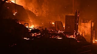 Fire burns makeshift tents outside the perimeter of the overcrowded refugee camp at the port of Vathy on the eastern Aegean island of Samos, Greece, late Sunday, 19 Sept. 2021