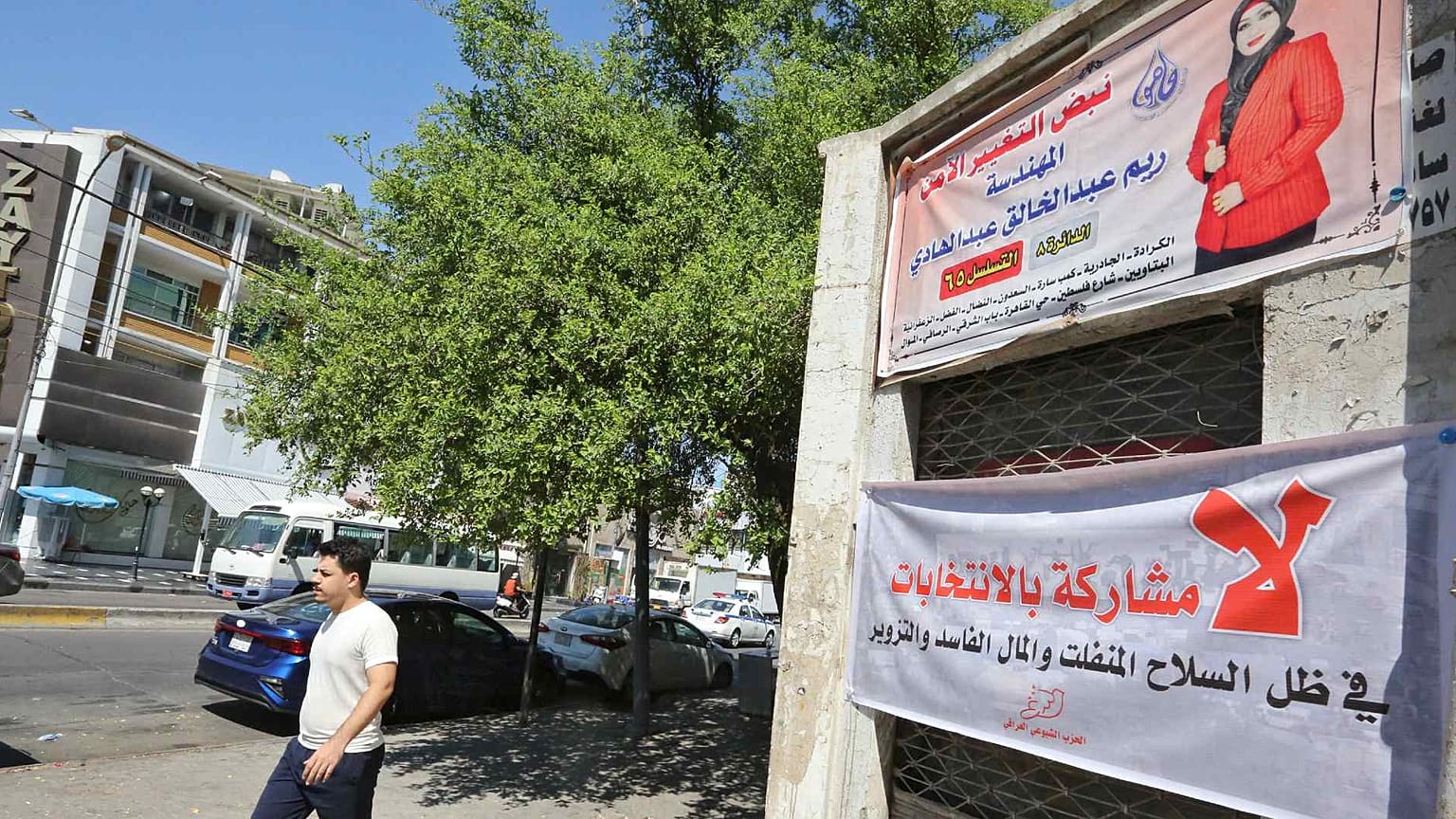 عراقي يمشي أمام اللوحات الإعلانية الانتخابية ولافتات المرشحين للانتخابات النيابية المقبلة في منطقة الكرادة بالعاصمة بغداد، 19 سبتمبر 2021