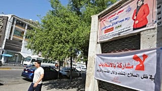 عراقي يمشي أمام اللوحات الإعلانية الانتخابية ولافتات المرشحين للانتخابات النيابية المقبلة في منطقة الكرادة بالعاصمة بغداد، 19 سبتمبر 2021