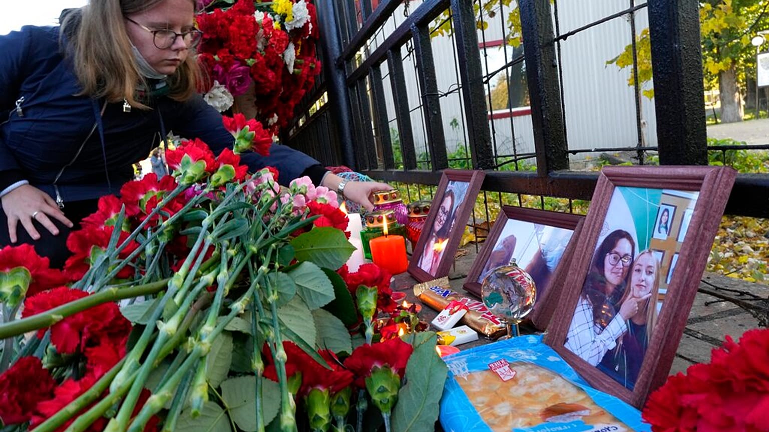A student places a candle next to flowers and portraits of victims of shooting, outside the Perm State University following a campus shooting in Perm.