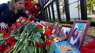 A student places a candle next to flowers and portraits of victims of shooting, outside the Perm State University following a campus shooting in Perm.