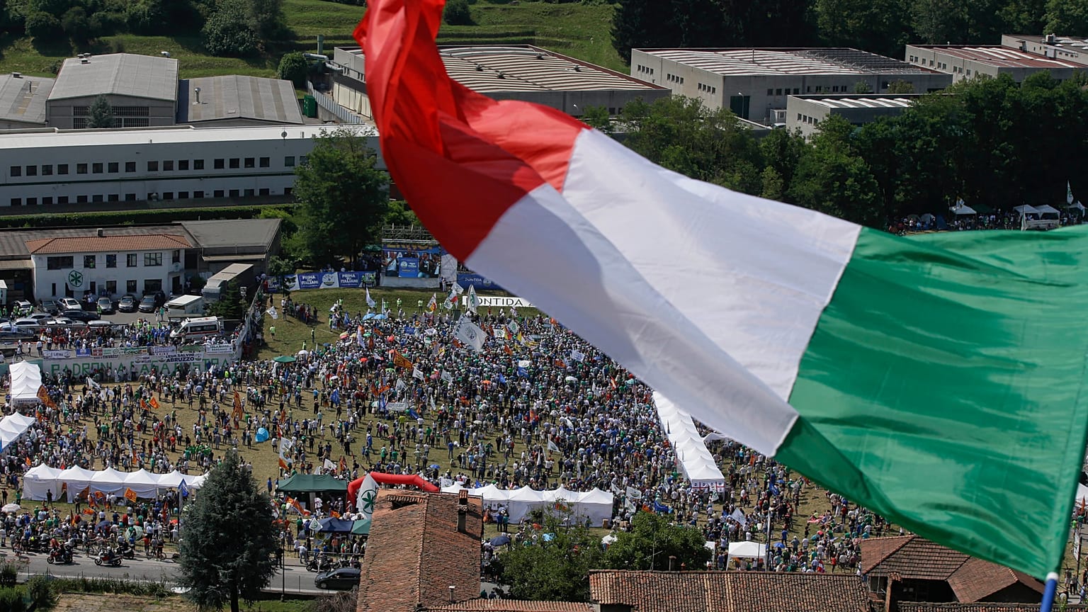 A man waves the Italian flag on a hill during a the traditional League party rally in Pontida in 2018.