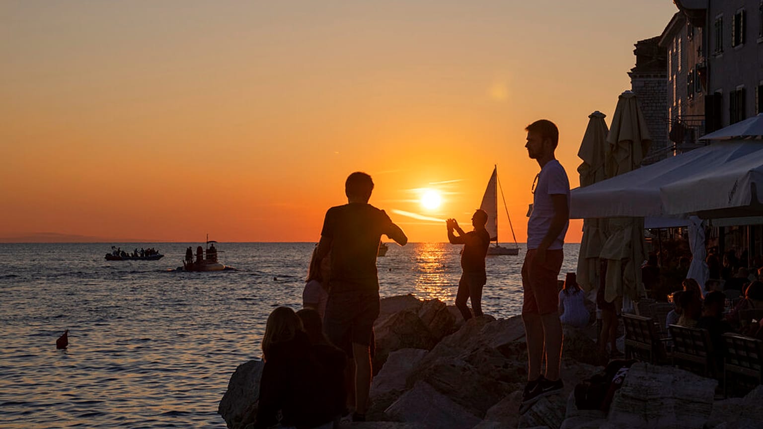 Holidaymakers enjoy the sunset on the seafront in the Adriatic town of Rovinj, Croatia, Friday, Aug. 27, 2021