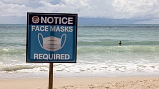 August 14, 2021 shows a sign reading "Face Masks Required" on Patong Beach in Phuket. 
