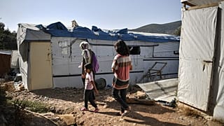One of the very few remaining families walk in the 'jungle' part of the Samos old Reception and Indentification center in Vathy, on September 19, 2021.