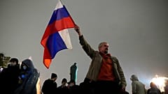 FILE - In this Sept. 20, 2021 file photo, a demonstrator holds a Russian national flag during a protest against the results of the Parliamentary election in Moscow, Russia. 