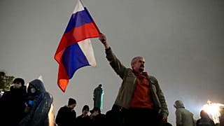 FILE - In this Sept. 20, 2021 file photo, a demonstrator holds a Russian national flag during a protest against the results of the Parliamentary election in Moscow, Russia.