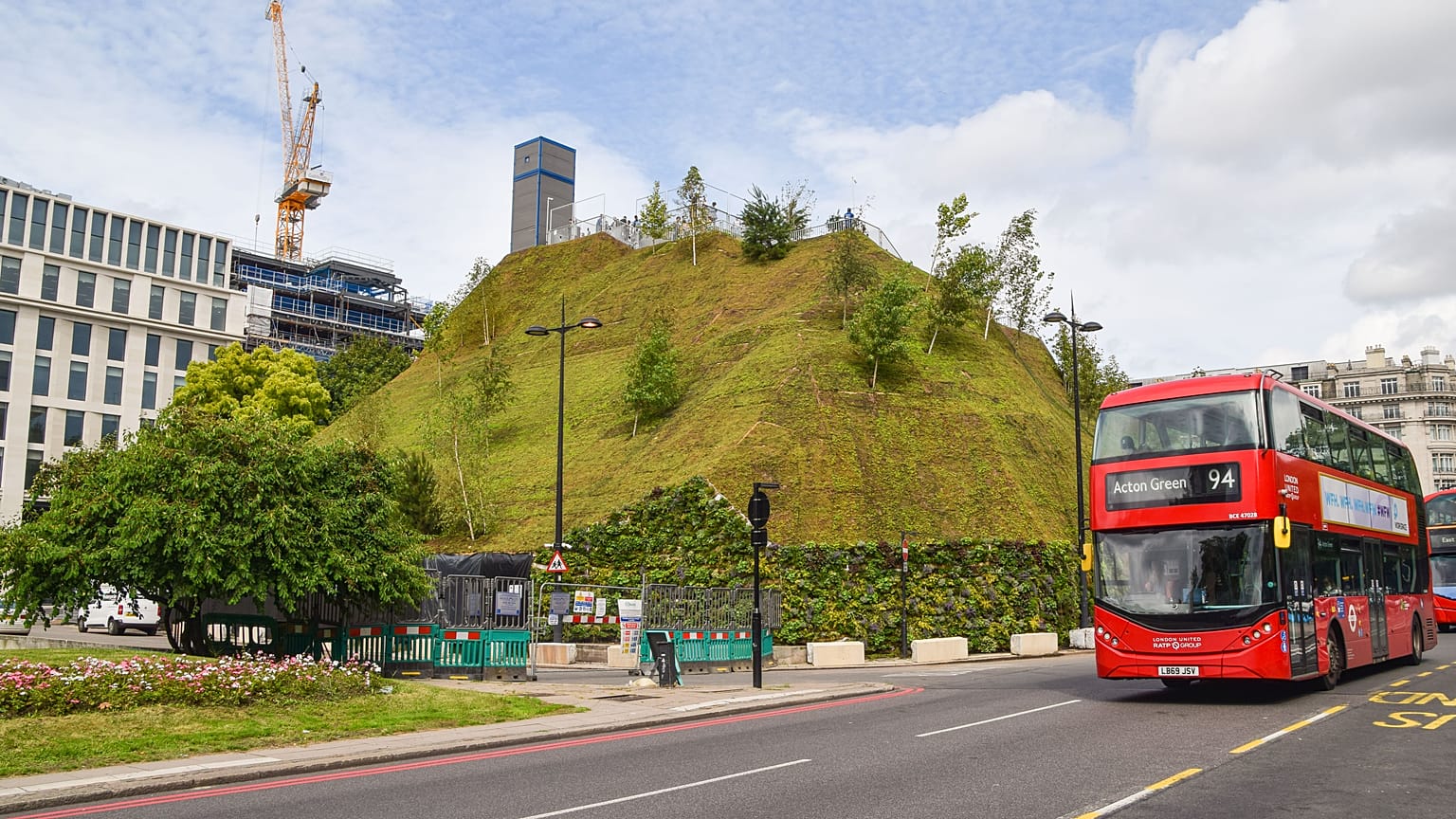 A bus drives past the recently reopened Marble Arch Mound.
