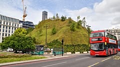 A bus drives past the recently reopened Marble Arch Mound.
