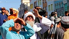 Menschen in Herat in Afghanistan blicken auf die an einem Kran hängenden Gehängten