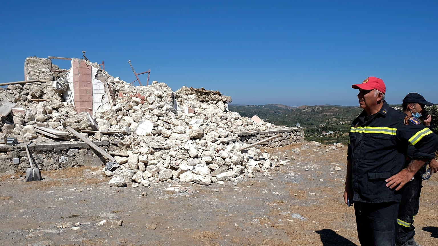 Firefighters stand next to a demolished Greek Orthodox church of Profitis Ilias after a strong earthquake in Arkalochori, on the island of Crete, Greece, Sept. 27, 2021.
