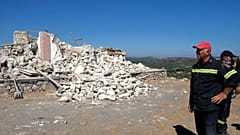 Firefighters stand next to a demolished Greek Orthodox church of Profitis Ilias after a strong earthquake in Arkalochori, on the island of Crete, Greece, Sept. 27, 2021.