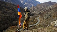 An ethnic Armenian soldier stands guard next to Nagorno-Karabakh's flag