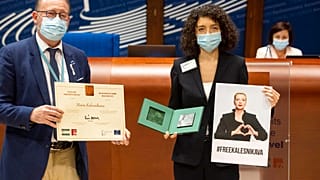 Parliamentary Assembly Rik Daems, left, holds a diploma while Tatiana Khomich holds a poster of jailed Belarus civil rights activist Maria Kalesnikava.