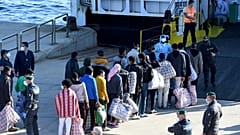 Migrants queue before boarding the GNV Azzurra ship after being transferred from the migrant centre on the Sicilian island of Lampedusa, May 13, 2021. 