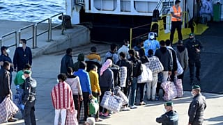 Migrants queue before boarding the GNV Azzurra ship after being transferred from the migrant centre on the Sicilian island of Lampedusa, May 13, 2021. 