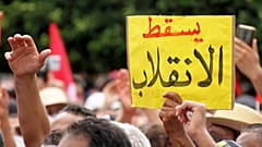 متظاهر يحمل لافتة  كتب عليها "يسقط الانقلاب" خلال مظاهرة ضد الرئيس التونسي قيس سعيد في العاصمة تونس الأحد 26 أيلول/ سبتمبر 2021