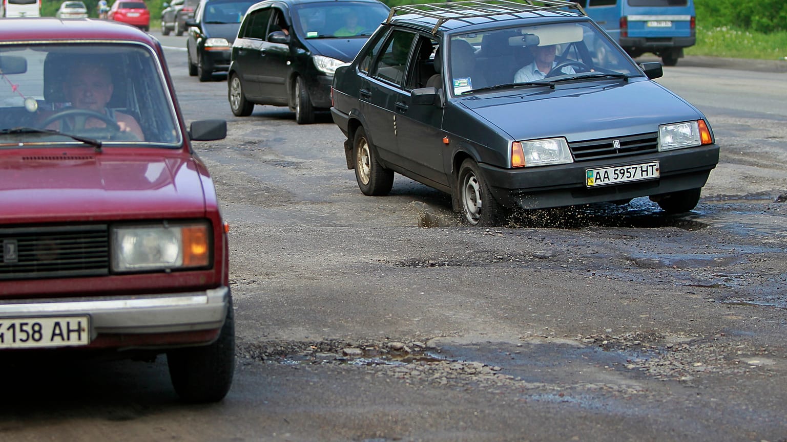 Cars drive over a pothole along a road near Kiev May 16, 2013. 