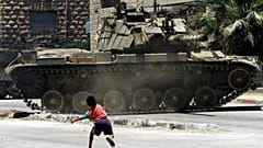طفل فلسطيني يرشق الحجارة باتجاه ناقلة جند إسرائيلية كانت تقوم بدوريات في مخيم الدهيشة للاجئين بالقرب من بيت لحم في 5 يوليو/تموز 2002 أثناء حظر التجول