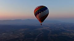A hot air balloon soars above the Tuscan countryside