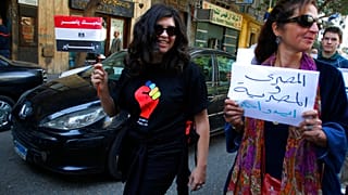 امرأة مصرية تحمل لافتة باللغة العربية كتب عليها: "رجل وامرأة مصريان في يد واحدة" في ميدان التحرير، وسط القاهرة للاحتفال باليوم العالمي للمرأة، مصر، 8 مارس 2011
