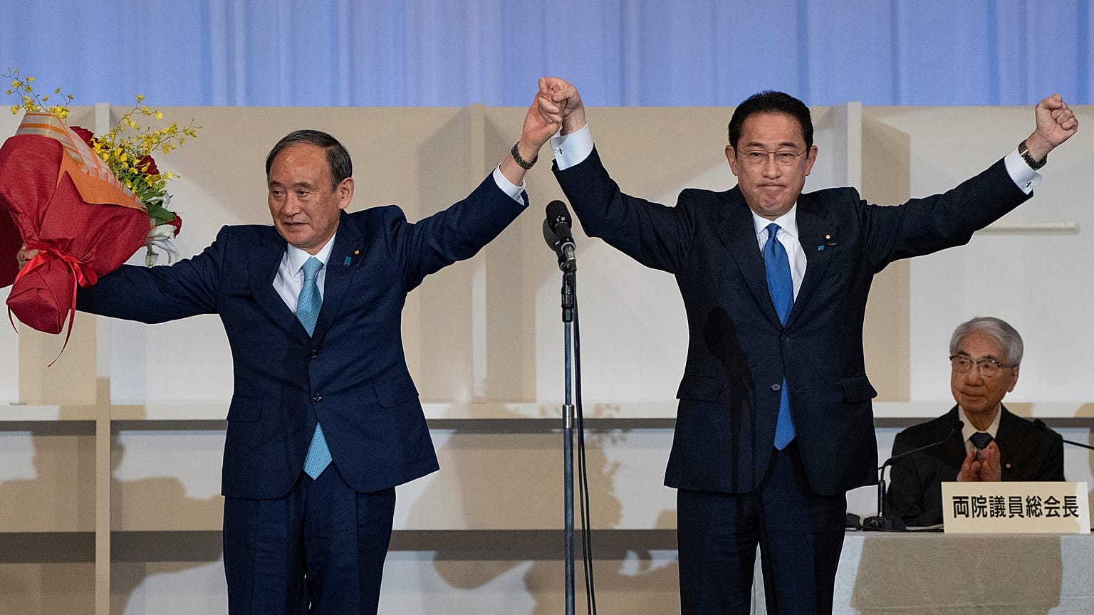 New Japanese Prime Minister Fumio Kishida, right, celebrates with outgoing Prime Minister Yoshihide Suga in Tokyo on September 29, 2021.