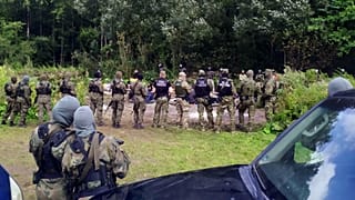 Belarus sınırından Polonya'nın Usnarz Gorny köyüne geçen sığınmacılar ve başlarında bekleyen Polonya sınır birlikleri
