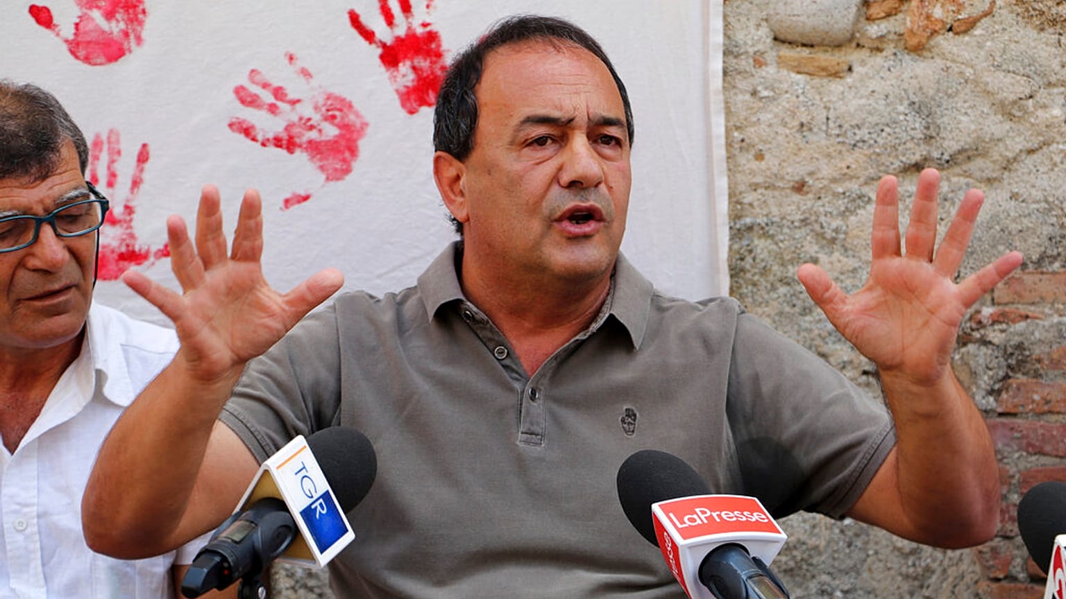 In this photo taken on Sept. 2019, the former mayor of Riace, in Southern Italy, Domenico "Mimmo" Lucano receives media attention.